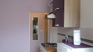 Een kleine keuken met een gasfornuis, een magnetron en een spoelbak.
