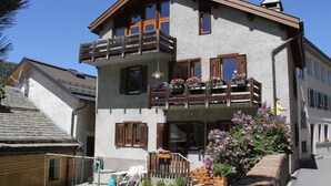 A multi-story building with balconies, a garden area, and a clear sky. - Chesa Madragena by Interhome (Pontresina)