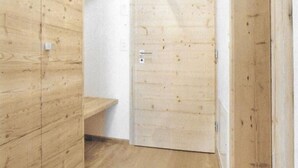 Una habitación de madera con una puerta y un pequeño estante de madera.