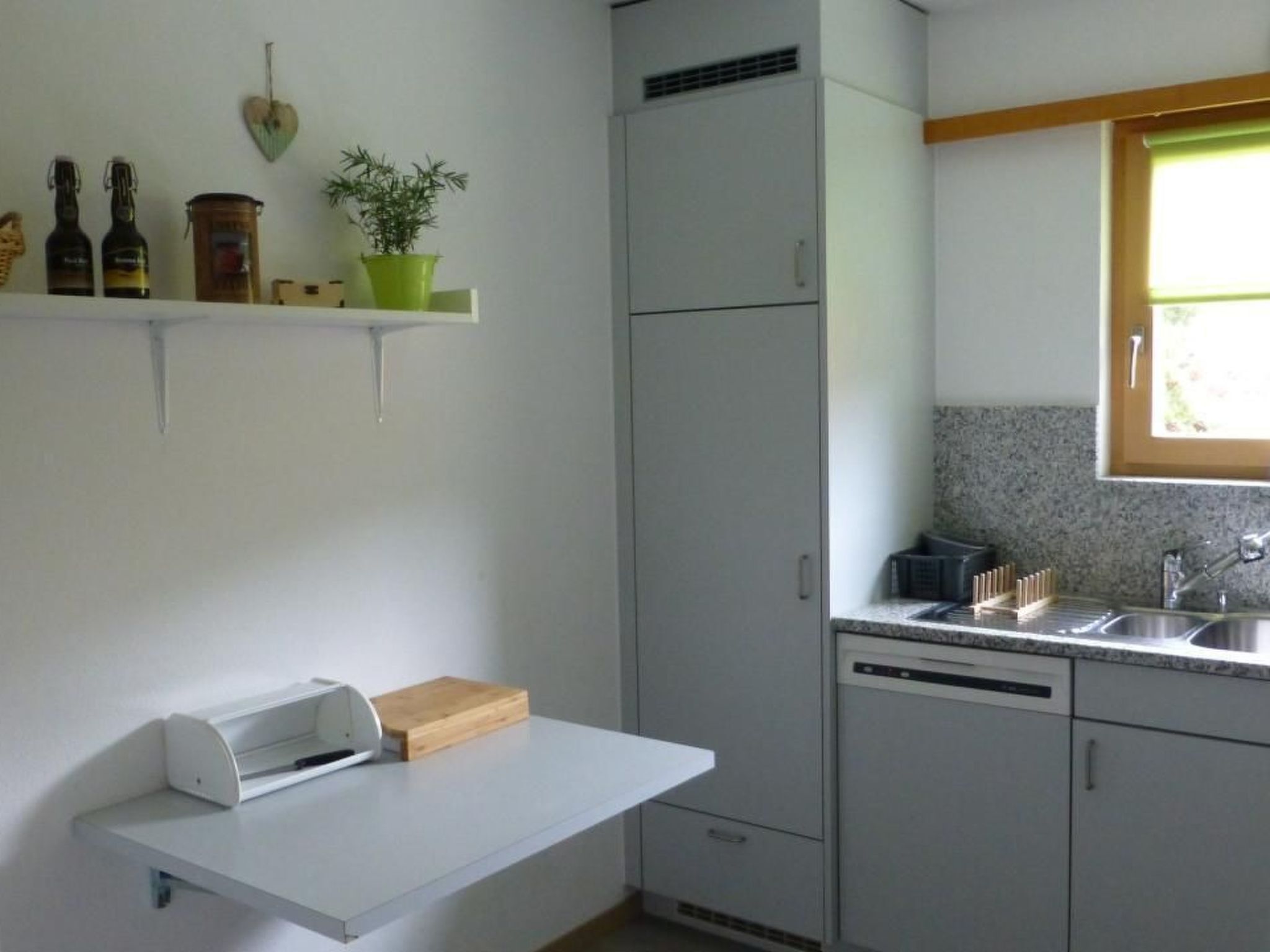 A compact kitchen with a built-in refrigerator, a small window, and a countertop with a sink.