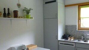 A compact kitchen with a built-in refrigerator, a small window, and a countertop with a sink. - Chesa Azalea 3 klein by Interhome (Pontresina)
