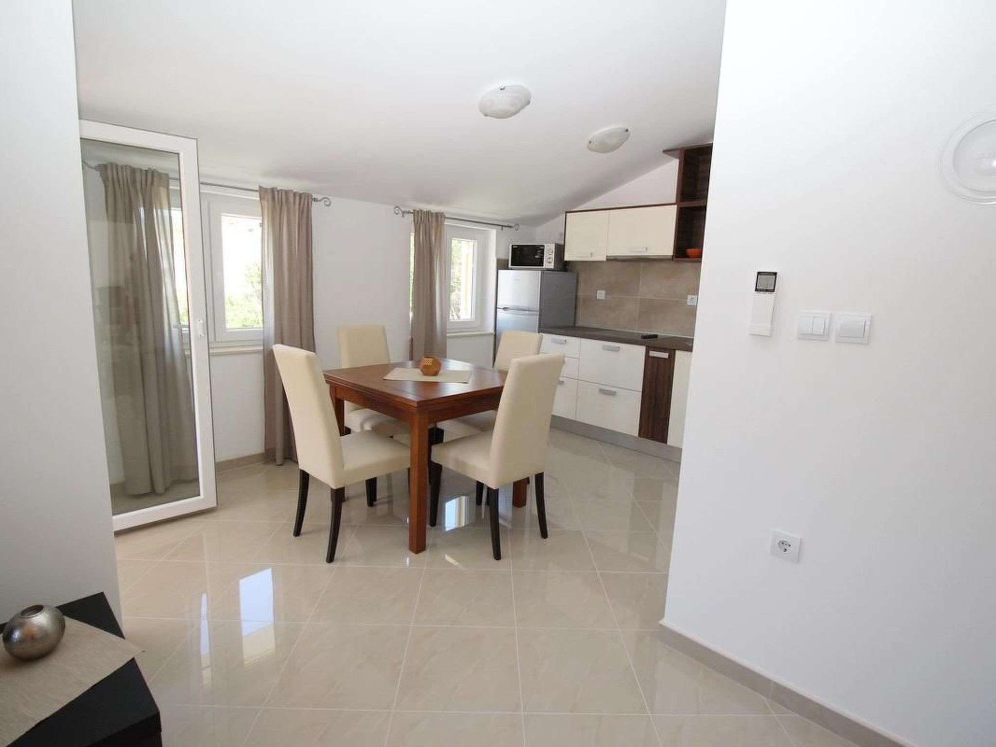 A modern kitchen with white cabinets, a microwave, and a stove. There is a dining area with a wooden table and four chairs.