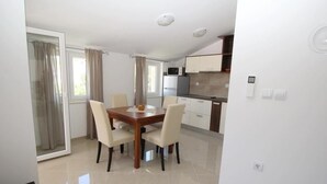 A modern kitchen with white cabinets, a microwave, and a stove. There is a dining area with a wooden table and four chairs. - Apartment Gorica by Interhome (Krk/Baška)