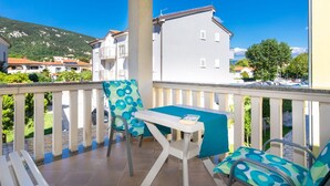 Ein Balkon mit Tisch und Stühlen, Blick auf Gebäude und einen Berg im Hintergrund.