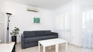 Ein modernes Wohnzimmer mit einem grauen Sofa, einem weißen Couchtisch, einer Stehlampe und einem Blumentopf.