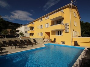 Ein gelbes Gebäude mit Schwimmbad und Liegestühlen.