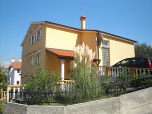 A yellow building with a red-tiled roof, a balcony, and a car parked in front. - Appartement in Baška mit Eigener Terrasse by Interhome (Krk/Baška)