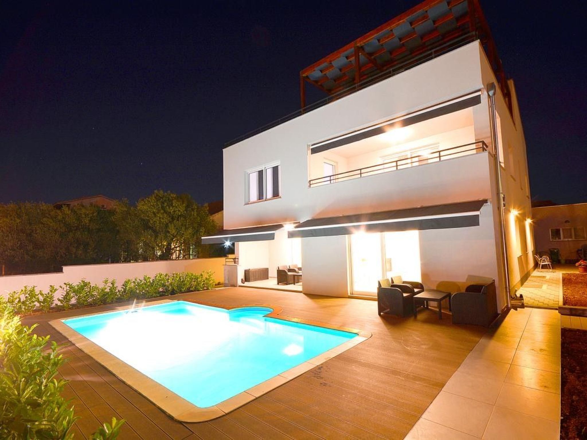 A modern two-story house with a swimming pool and outdoor seating area.