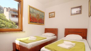 Ein Zimmer mit zwei Holzbetten, weißen Leinentüchern, grünen Handtüchern und einem Bild an der Wand.