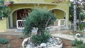 Ein Gebäude namens "Villa Stefany" mit einem angelegten Garten, der einen zentralen Baum und einen Kiesweg zeigt.