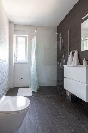 Ein modernes Badezimmer mit freistehender Badewanne, einer gläsernen Dusche und einem weißen Waschtisch.