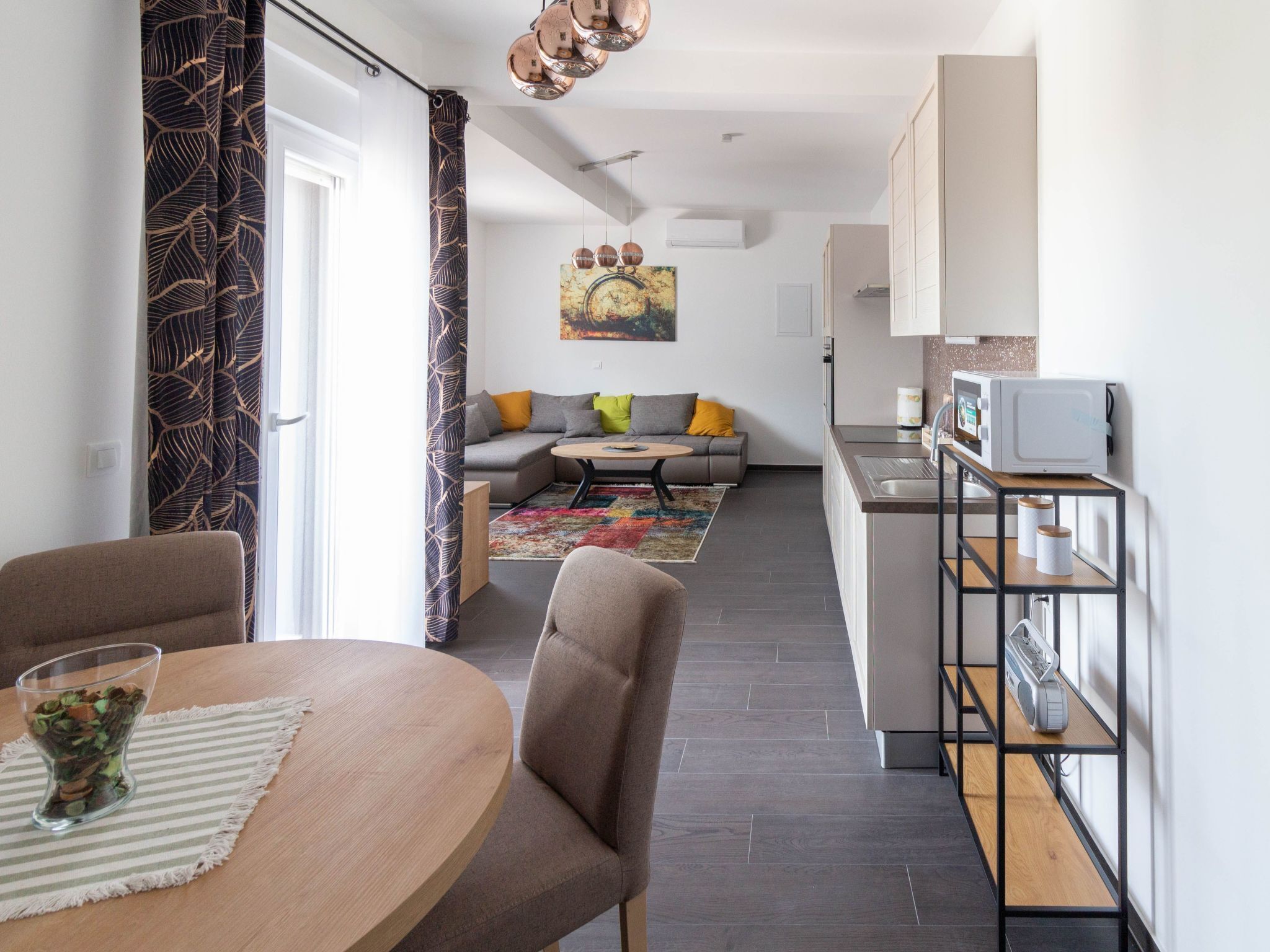 Ein moderner Wohnbereich mit Essplatz, Sofa, Küche und Kunstwerk an der Wand.