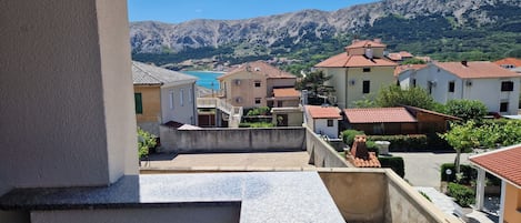 A residential area with terraced houses, a clear blue sky, and mountains in the background.