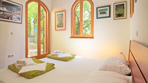 Une chambre avec deux lits, de grandes fenêtres et des œuvres d’art accrochées aux murs.