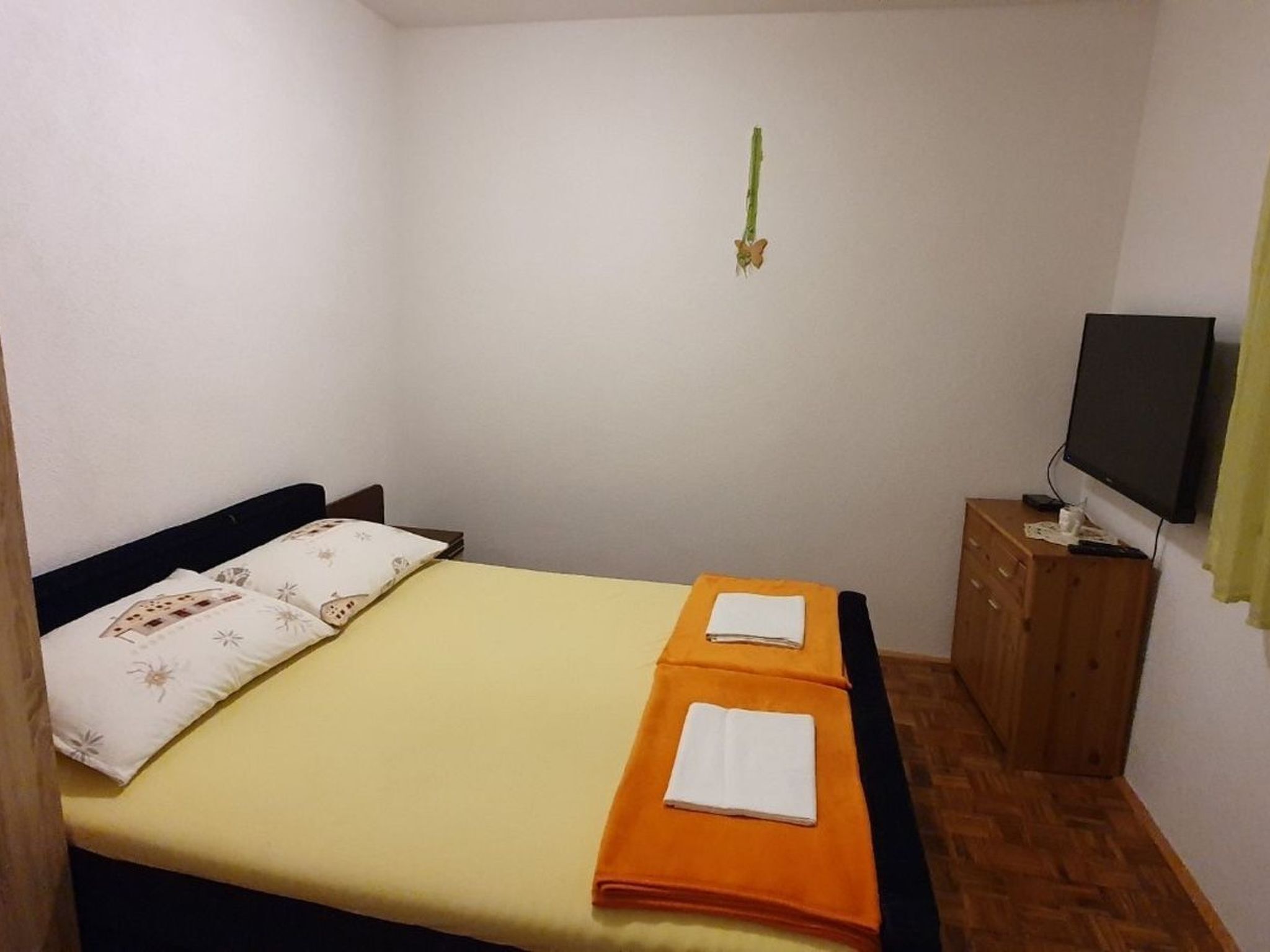 Una habitació petita i senzilla amb un llit, una televisió i un armari de fusta.