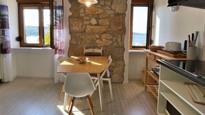 Une cuisine moderne avec un mur en pierre, un plancher en bois et un coin repas comprenant une table et des chaises.