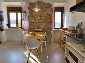 A modern kitchen with a stone wall, wooden flooring, and a dining area with a table and chairs. - Apartment Gorisek mit Meerblick by Interhome (Polje)
