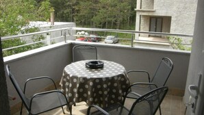 Ein Balkon mit einem runden Tisch, bedeckt mit einer Tischdecke mit Punkten, umgeben von Metallstühlen.