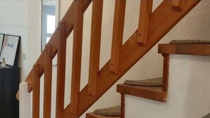 Een houten trap met tapijttegels en een witte muur.