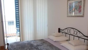Ein Schlafzimmer mit einem Bett, einem Fenster mit Jalousien und einem Bild an der Wand.