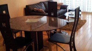 Ein Essbereich mit einem runden Tisch, vier Stühlen, einer Couch und einem Couchtisch.