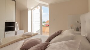 A bedroom with a bed, pillows, a bedside table, a wardrobe, and a sliding glass door leading to an outdoor balcony. - Apartment  Medanic 3 by Interhome (Privlaka)