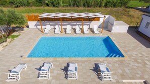 A rectangular swimming pool with a wooden deck and white lounge chairs. - Apartment  Medanic 3 by Interhome (Privlaka)