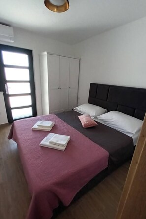 A bedroom with a bed, a wardrobe, and a door with a window. - Jacuzzi Haus by Interhome (Posedarje)