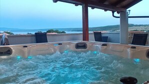 Un bain à remous avec vue sur la mer, installé sous une structure de toit en bois.
