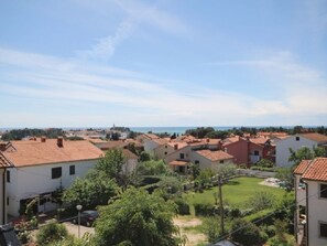 Ein Wohngebiet mit Häusern mit Terrakotta-Dächern, einem Rasen und weiter Aussicht auf das Meer.