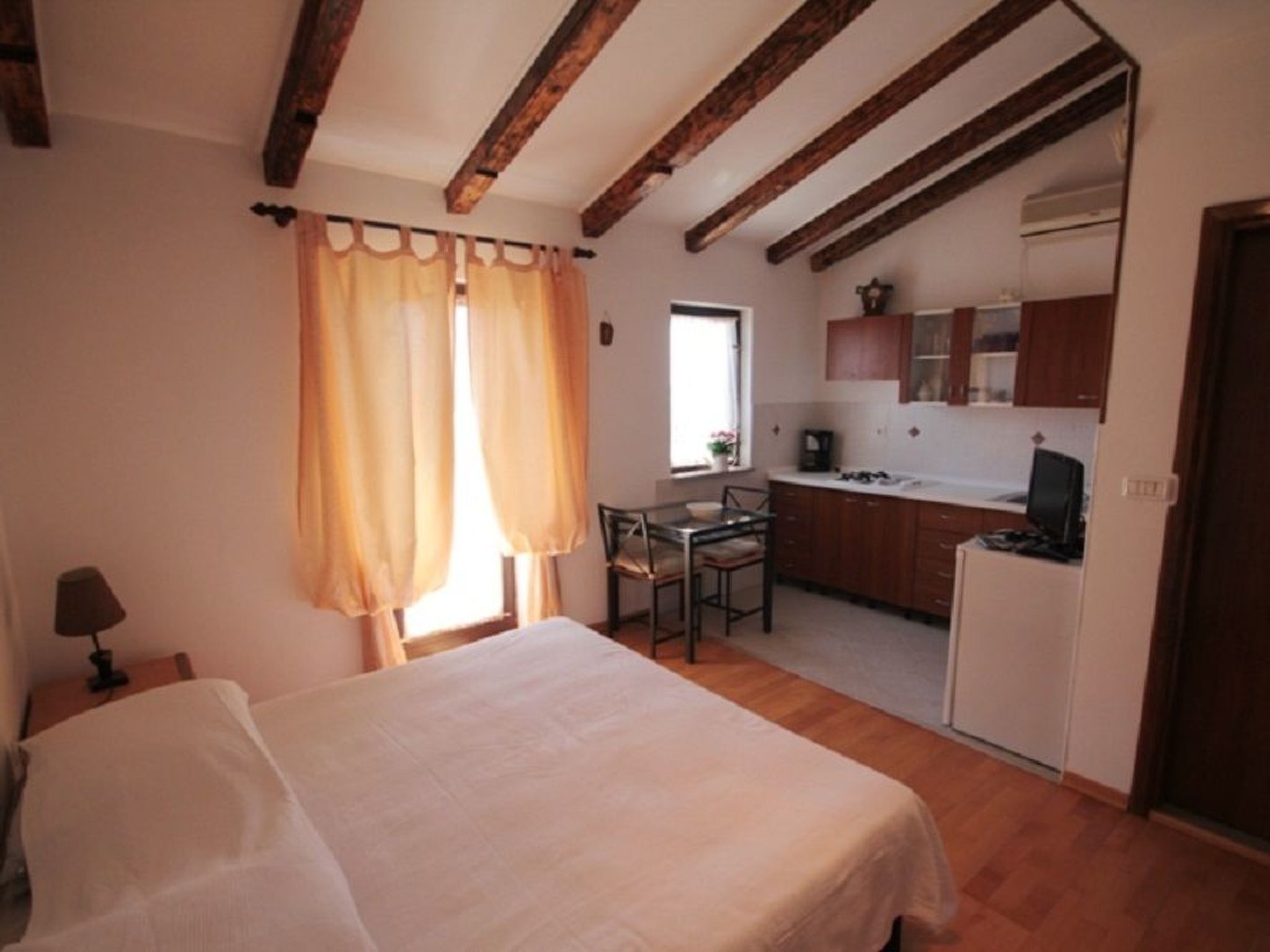 Ein Schlafzimmer mit Bett, Schreibtisch und einer kleinen Küche im Hintergrund.
