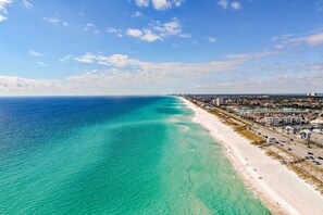 Un paisaje urbano costero con una extensa playa de arena y un mar azul cristalino.