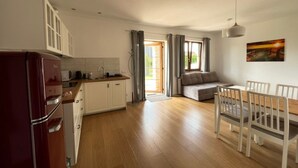 A modern kitchen with a refrigerator, cabinets, and a dining area with a table and chairs. - Komfortable Wohnung mit Garten, in der Nähe des Meeres by Interhome (Sarbinowo)