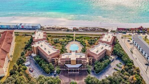 Un hotel con piscina central, rodeado de exuberante vegetación y vistas a la playa.
