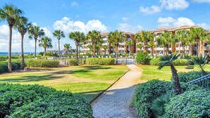 Un hotel con un patio central, palmeras y un camino que lleva al edificio.