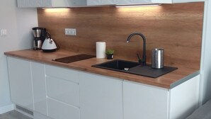Une cuisine moderne dotée d’un plan de travail en bois, de deux éviers, d’une machine à café et d’une bouilloire.