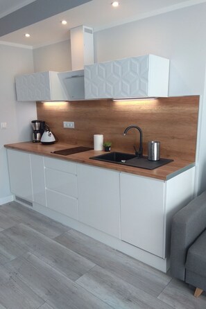 A modern kitchen with a wooden countertop, two sinks, a coffee maker, and a kettle. - Apartament Cesarski Agnes by Interhome (Swinoujscie)
