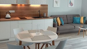 Une cuisine moderne avec un coin repas, un canapé gris agrémenté de coussins colorés et une petite table.