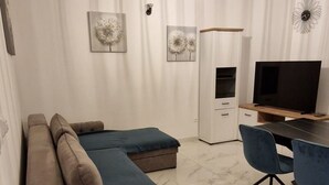 Un dormitorio moderno con un sofá modular, un escritorio con silla, un televisor y decoración mural.