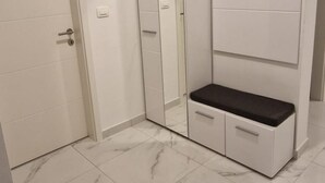 Una habitación con un armario blanco, un banco y una puerta.
