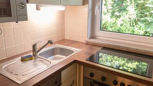 Una cocina con un fregadero, estufa y ventana con vistas a la vegetación.