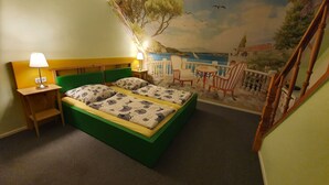 Ein Schlafzimmer mit einem Bett, zwei Nachttischen, einer Lampe und einem Wandbild mit einer Strandansicht.
