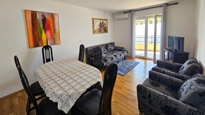 A dining area with a table and chairs, a sofa, and a television. - Wohnung mit Meerblick, 150 m vom Strand entfernt by Interhome (Novi Vinodolski)