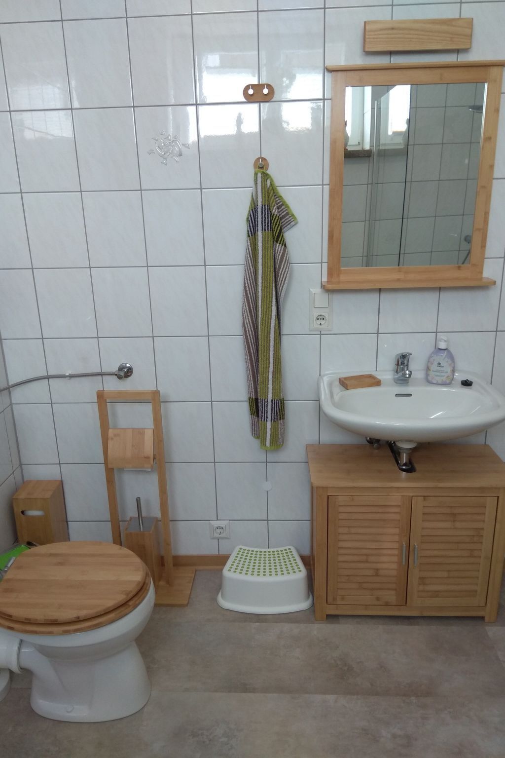 Une salle de bain comprenant des toilettes, un meuble en bois, un lavabo et un miroir.