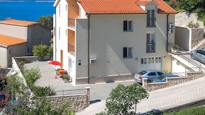 A multi-story building with a red-tiled roof, a balcony, and a view of the sea. - Wohnung "Apartman für 4 Personen" by Interhome (Brela)