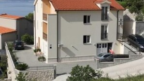 A two-story building with a red-tiled roof, a balcony, and a parking area with cars. - Studio im Erdgeschoss für zwei Personen mit einer Terrasse by Interhome (Brela)