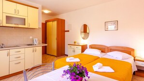 A hotel room with two beds, a small kitchenette, a bathroom, and a dining area. - Studio im Erdgeschoss für zwei Personen mit einer Terrasse by Interhome (Brela)
