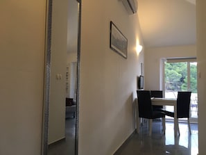 Una habitación de hotel moderna con comedor, un espejo grande y vistas al exterior.