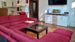 A living room with a red sofa, a glass coffee table, and a TV mounted on the wall. - Appartement mit eigenem Parkplatz by Interhome (Jüterbog)