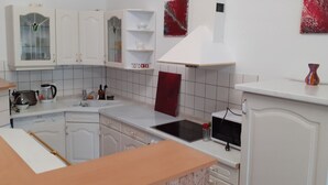 A kitchen with white cabinets, a microwave, a sink, and a red decorative piece on the wall. - Appartement mit eigenem Parkplatz by Interhome (Jüterbog)